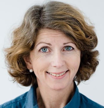 Smilende kvinne med halvlangt brunt hår og blå skjorte