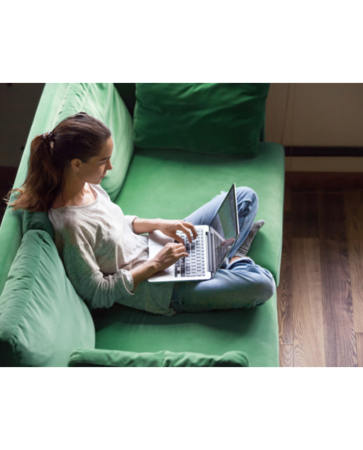 Student sitter i sofa med laptop på fanget.