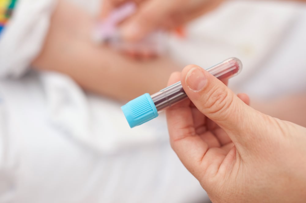 Blodprøverør i hånden til en helsearbeider. Foto: Annette Larsen